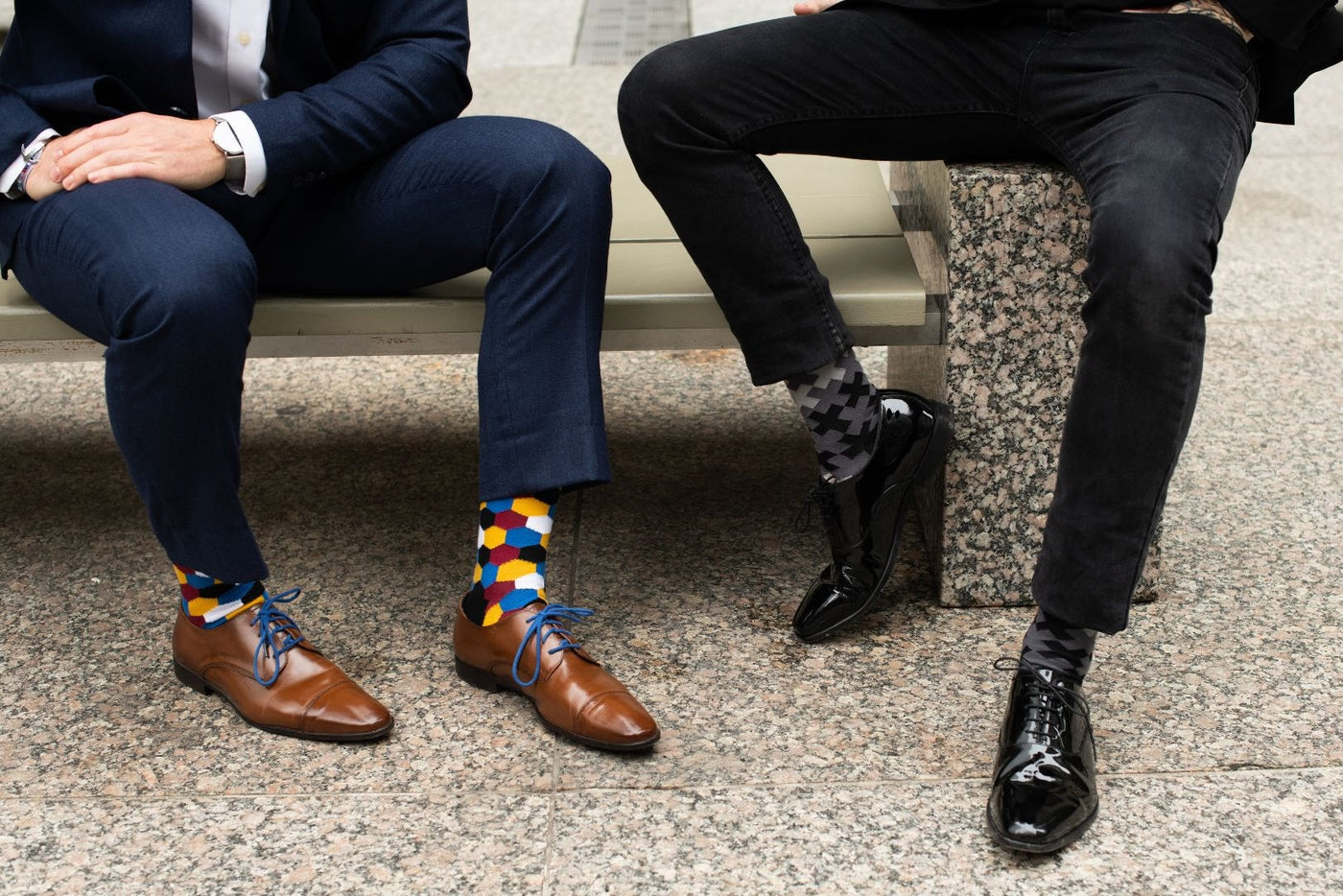 two people sitting on a bench showing off their socks