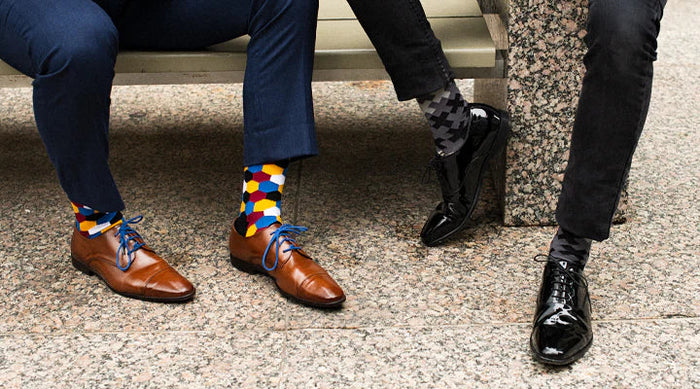 two people showing off their socks wearing suits and dress shoes