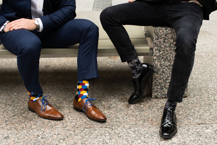 two people sitting on a bench showing off their socks