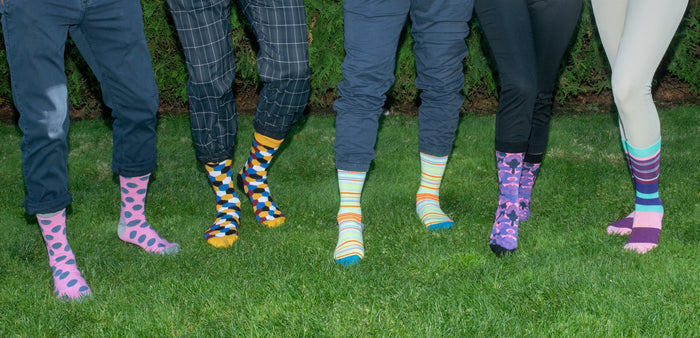 five people wearing colorful socks standing on grass