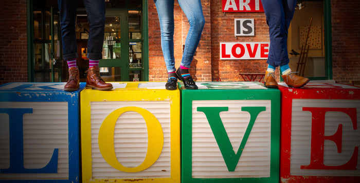 three people wearing colorful socks standing on blocks that spell out 